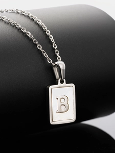 Macro view of square shell pendant featuring letter B on a polished silver chain