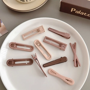 Collection of brown and beige seamless hair clips arranged on a white ceramic plate