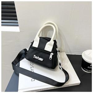 Close-up of color-block mini bag with Tochaso logo on books beside a coffee cup