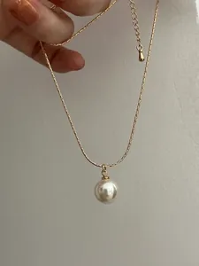 Close-up of a large white pearl pendant on a gold snake chain with adjustable clasp