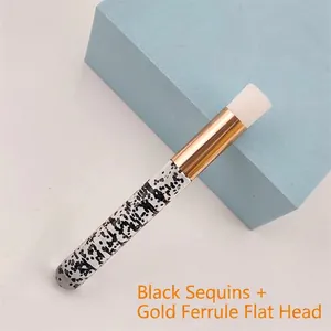 Close-up of portable eyelash cleanser brush with glitter black handle and gold flat head