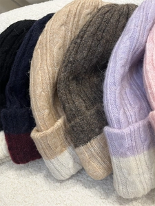 Detailed view of color-block knit beanies in various shades with thick cable patterns
