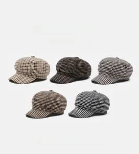 Flat lay of vintage plaid newsboy caps in five colors with soft houndstooth texture