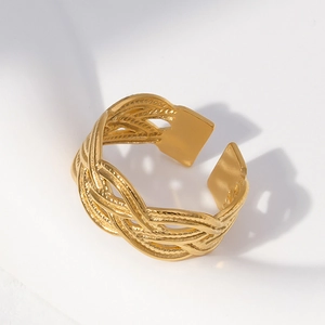 Detail eines goldfarbenen geflochtenen Edelstahlrings mit offenem Design auf Stoff