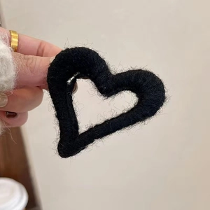 Close-up of a black heart-shaped plush hair claw clip showing soft furry texture and detail