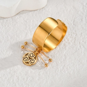 Gold open ring with transparent beads and spiral pendant on textured white surface