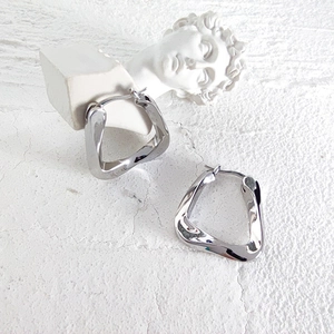 Close-up of silver irregular twisted geometric hoop earrings with high polish finish