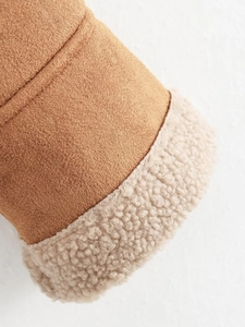 Detailaufnahme von braunem Wildlederimitat mit weichem cremefarbenem Lammfellfutter