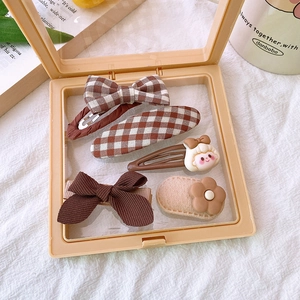 Detailed set of 5 brown fabric hair clips including bows and floral patterns in a display box