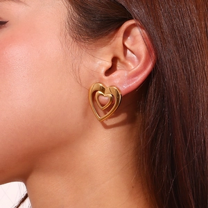Close-up of double layered heart-shaped gold earrings shown on a model's ear