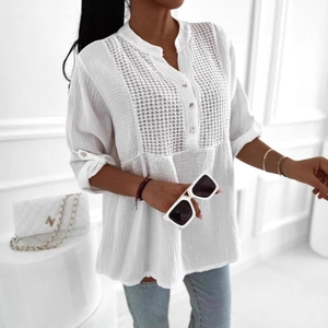 Detail of elegant white V-neck blouse featuring lace patchwork and buttoned cuffs