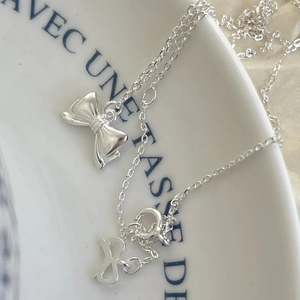 Elegant 925 sterling silver bow pendant necklace with refined silver chain on ceramic dish