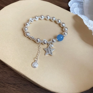 Detail of silver brushed beads bracelet with star charm and blue bead on lace background