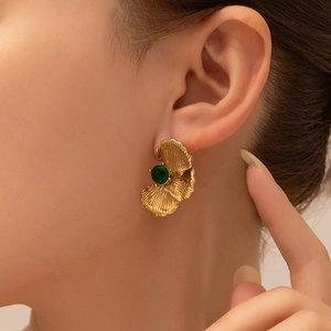 Close-up of vintage gold ginkgo leaf earrings with a round green zircon stone on ear