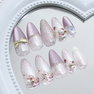Purple and cream almond press-on nails with 3D gold bows, pearls and flower nail art