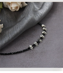 Macro shot of Gothic black beaded necklace with vintage silver skull pendants details