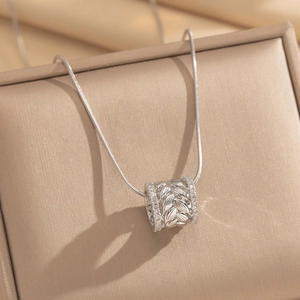 Close-up detail of silver wheat ear cylindrical necklace pendant with paved crystals