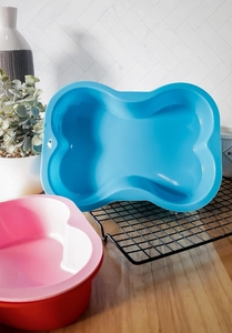 Detailed view of bone-shaped silicone baking molds in blue and pink on a kitchen counter