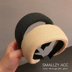 Detailed view of wide knitted headbands in dark grey and beige with soft wool texture