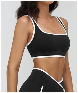 Detail shot of black sports bra with white contrast piping and ergonomic high-waist fit