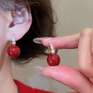 Macro detail of red zircon earrings featuring gold finish and sparkling crystal accents