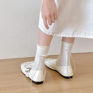 White frilly mid-tube socks with ribbon bows worn with matte Mary Jane shoes