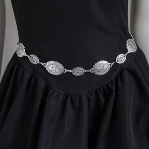 Detail of vintage silver chain belt with embossed oval metal plates on black dress