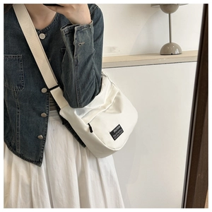 Detail of white nylon shoulder bag with wide strap and branded tag in mirror selfie view