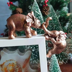 Close-up of bronze resin elephant ornaments helping each other on a frame