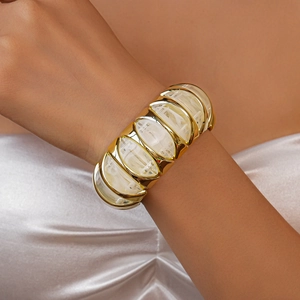 Detailed close-up of wide acrylic resin bangle with gold-tone frames on wrist
