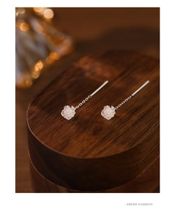 Macro shot of iridescent white rose earrings with elegant long silver tassel chains