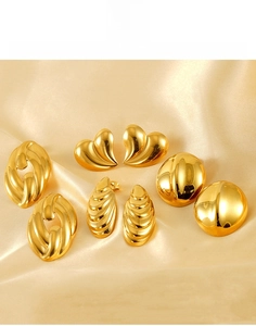 Detailed view of 18K gold plated heart and textured steel earrings on satin fabric