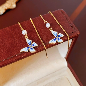 Detail of 14K gold plated butterfly tassel earring with blue enamel and pearl drop