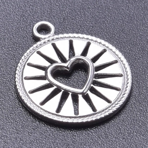 Close-up of a silver round pendant featuring a hollow heart center and sunburst detailing