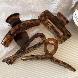 Set of four tortoiseshell hair claws in vintage amber finish on a white textured background