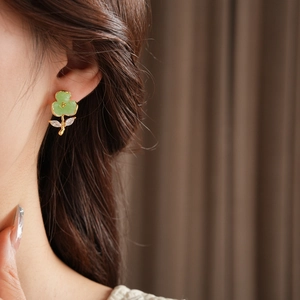 Close-up of elegant green crystal flower stud earrings worn by a model in warm lighting