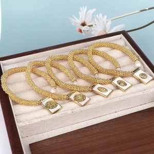 Close-up of five golden beaded bracelets with religious pendants in a wooden jewelry box