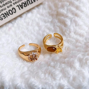 Detail of vintage gold plated open rings with tiger eye stone and zircon on white fabric