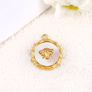 Macro detail of gold-plated bee pendant with white shell inlay and textured surface