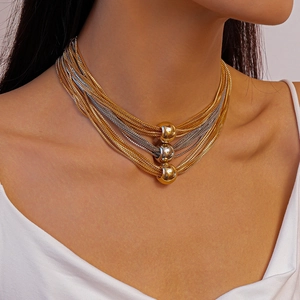 Detail of layered gold and silver mixed metal chains with polished beads on neckline