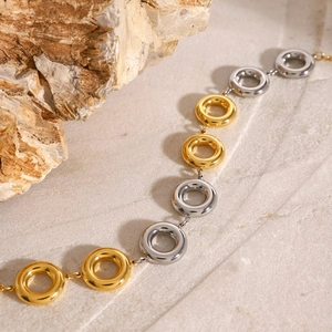 Detailed shot of two-tone gold and silver circular chain links on a marble surface