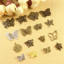 Flat lay of vintage butterfly alloy pendants in bronze, white K and gold for DIY crafts