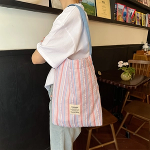 Détail du sac cabas en toile rayée montrant la texture gaufrée et l'étiquette