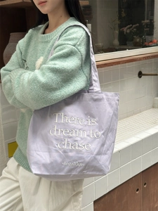 Detail of light purple canvas tote bag with white embroidery on a shoulder strap
