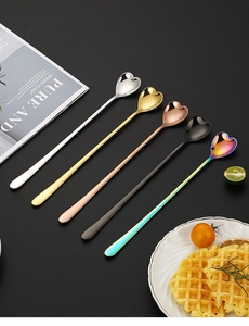 Top-down view of five heart-shaped stainless steel long handle spoons in assorted colors