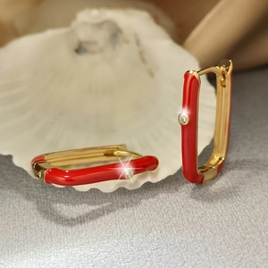 Detail of gold-plated rectangular earrings with red enamel and shimmering cubic zirconia