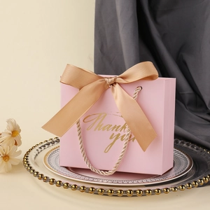 Detailed shot of pink wedding gift bag with golden bow and Thank You engraving