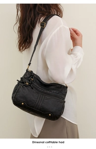 Détail d'un sac bandoulière vintage en cuir noir avec poches zippées et rivets dorés
