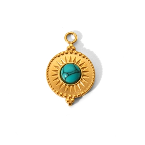 Macro shot of gold sunburst pendant with turquoise stone inlay and beaded rim