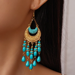 Close-up of model wearing bohemian crescent moon tassel earrings with turquoise beads